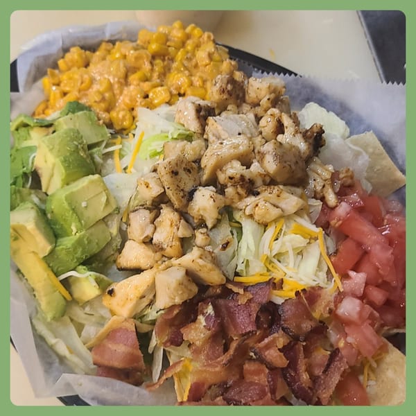 A Santa Fe Taco Company salad bowl with chicken, avocado, corn, bacon, tomatoes, and lettuce.